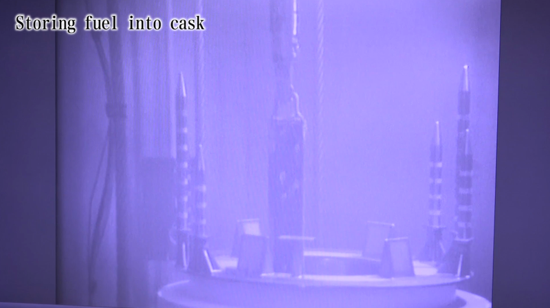 A spent fuel rod being lowered into a cask for storage.